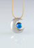 platinum pendant in the shape of a moon set with 2 small diamonds. An 18ct yellow gold setting hold an Eyris blue pearl. Hanging on an 18ct yellow gold chain