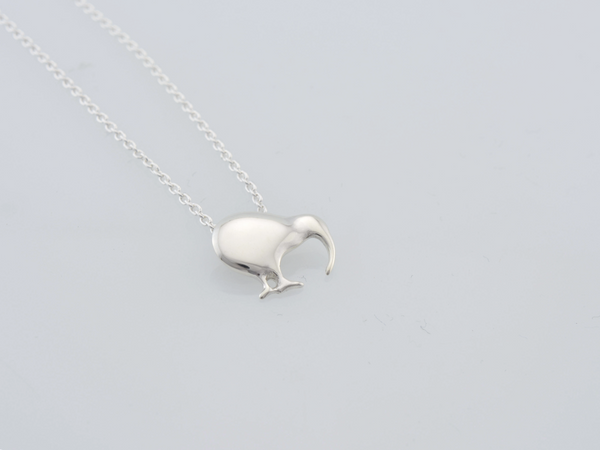 A silver pendant necklace featuring a minimalist kiwi bird pendant on a delicate silver chain, photographed against a clean, light gray background.